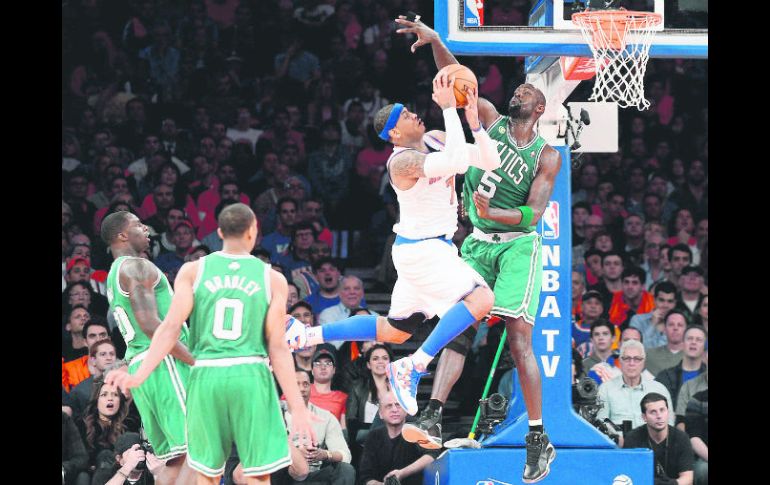 Imparable. Carmelo Anthony (blanco) recibe una falta de Kevin Garnett (derecha) en su intento por anotar. EFE /