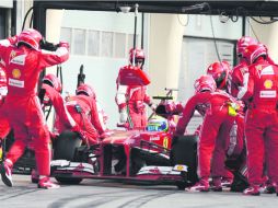 Mecánicos de Ferrari reemplazan los neumáticos del auto de Felipe Massa, luego de que se destrozara la goma derecha trasera. AFP /