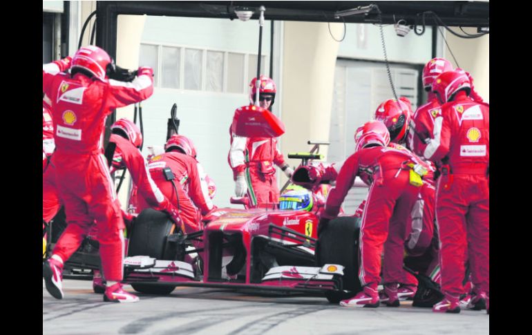 Mecánicos de Ferrari reemplazan los neumáticos del auto de Felipe Massa, luego de que se destrozara la goma derecha trasera. AFP /