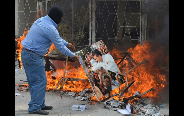 En la imagen, uno de los manifestantes quema una fotografía de Enrique Peña Nieto. AP /