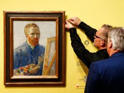 Dos curadores del museo colocan un autorretrato de Van Gogh en el que se pintó con un lienzo y paleta de pintor. AP /