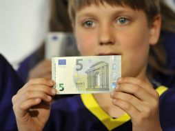 Un niño sostiene un ejemplar del nuevo billete de cinco euros. AFP /