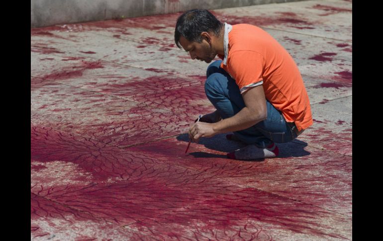 Imran Qureshi pintando su instalación ''¿Cuántas lluvias se necesitarán para borrar estas manchas de sangre?''. EFE /