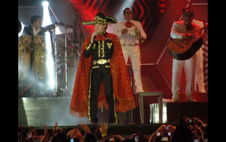 Pedro Fernández, defendiéndose de la lluvia y obsequiando al público con sus canciones en un lluvioso Acapulco 2013. NTX /