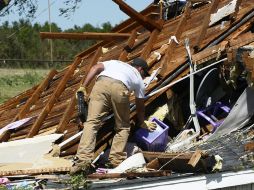 Un hombre trata de rescatar algunas de sus propiedades de su casa, destruida por el tornado. EFE /