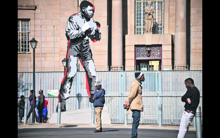 Cautela. Ciudadanos pasan a un lado de la estatua que representa al ex gobernante, en el Centro de Johanesburgo. AFP /