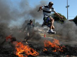 Manifestantes saltan por una barricada de fuego durante la marcha. EFE /