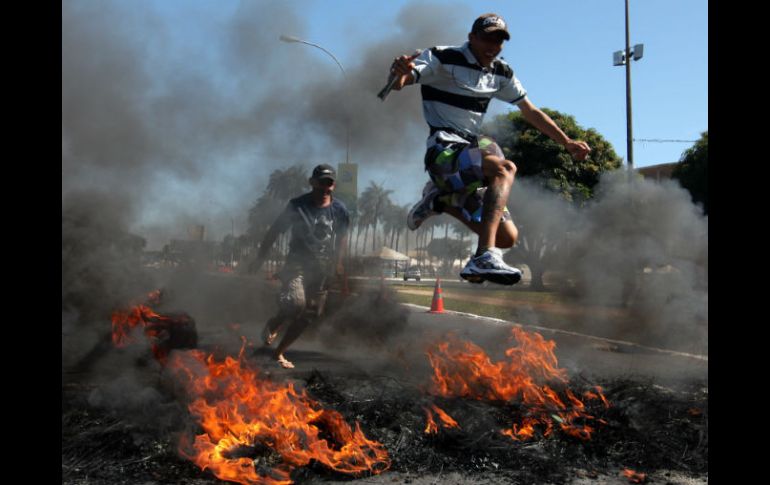 Manifestantes saltan por una barricada de fuego durante la marcha. EFE /