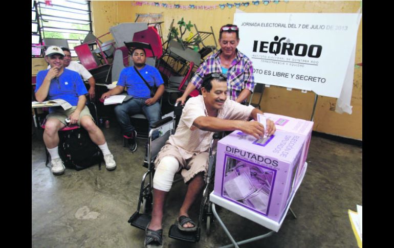 Un hombre lesionado es auxiliado por otra persona para emitir su sufragio en Cancún. EFE /