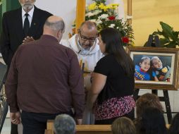 Un sacerdote habla con los padres de los niños fallecidos durante la misa. AP /