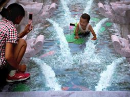 No es una fuente, es una pintura 3D donde una madre y su hijo imaginan refrescarse ante la oleada de calor. AP /