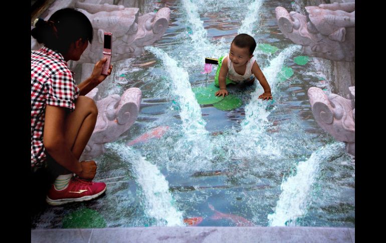 No es una fuente, es una pintura 3D donde una madre y su hijo imaginan refrescarse ante la oleada de calor. AP /