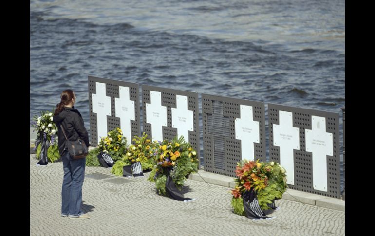 Una turista y frente a varias coronas de flores que han sido depositadas en un monumento levantado en recuerdo a las víctimas del Muro. EFE /