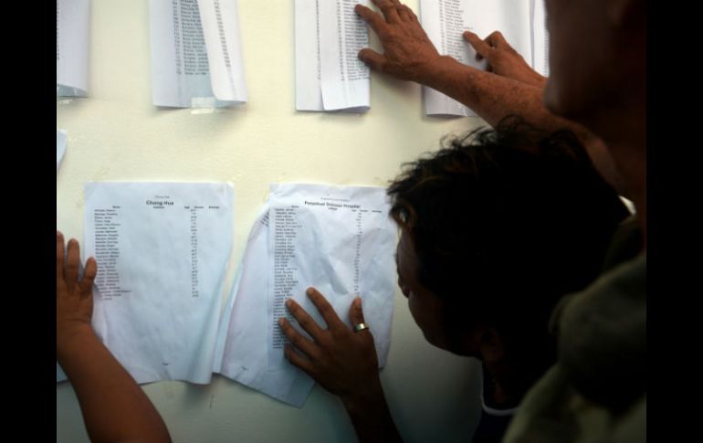 Familiares de los desaparecidos buscan entre las listas los nombres de sus parientes. AFP /