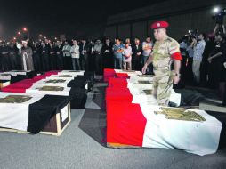 Personas se reúnen junto a los féretros de los policías muertos en El Arish (Egipto), en su funeral en el aeropuerto militar de Almaza.  /