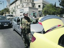 Un soldado sirio revisa un vehículo en el centro de Damasco, luego de ataques esporádicos de los rebeldes en la capital siria. AP /