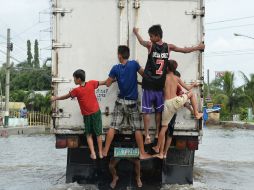 Niños afectados por las inundaciones viajan en la parte trasera de un camión. AFP /