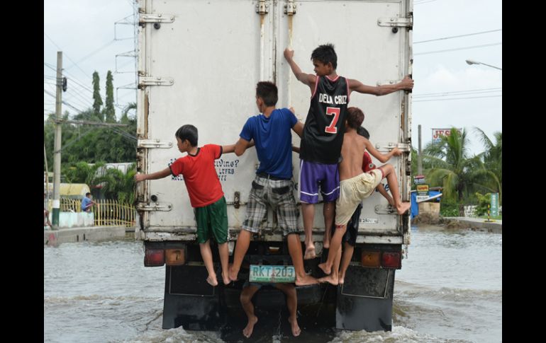 Niños afectados por las inundaciones viajan en la parte trasera de un camión. AFP /