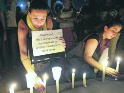 Mujeres sirias que viven en Beirut, encienden velas durante una vigilia por las víctimas del presunto uso de armas químicas en  Damasco AP /