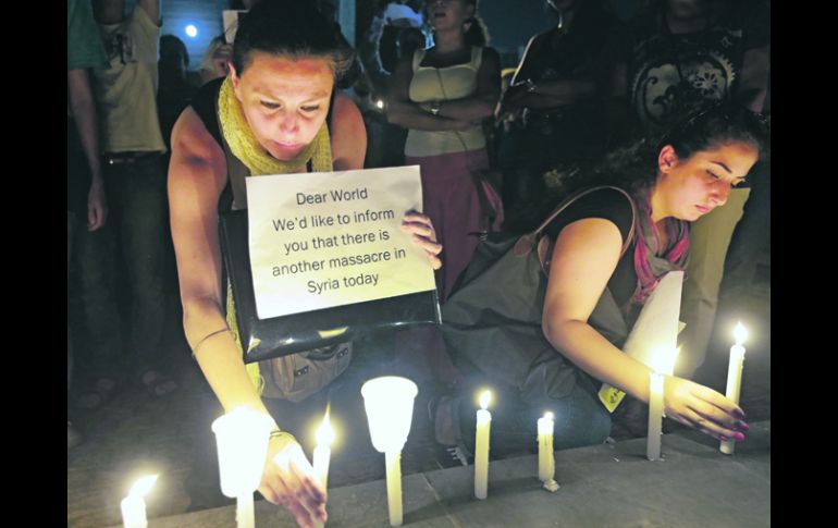 Mujeres sirias que viven en Beirut, encienden velas durante una vigilia por las víctimas del presunto uso de armas químicas en  Damasco AP /