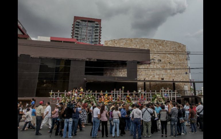 Familiares de las víctimas del incendio colocan flores a las afueras de lo que antes era el casino Royale. ARCHIVO /