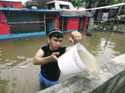 n hombre trata de desalojar el agua que invadió su vivienda en Veracruz, ante las tormentas provocadas por el fenómeno natural. AFP /