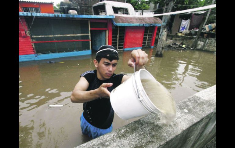 n hombre trata de desalojar el agua que invadió su vivienda en Veracruz, ante las tormentas provocadas por el fenómeno natural. AFP /