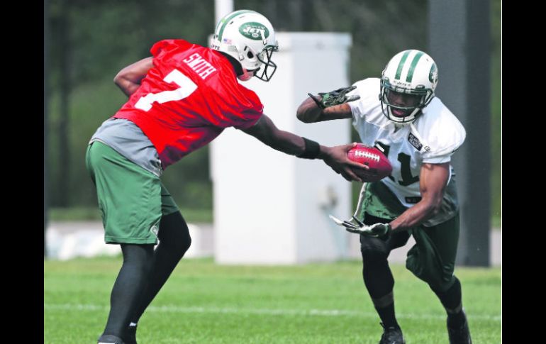 El pasador novato Geno Smith le entrega el ovoide al corredor Mossis Madu, durante el entrenamiento de los Jets. AP /