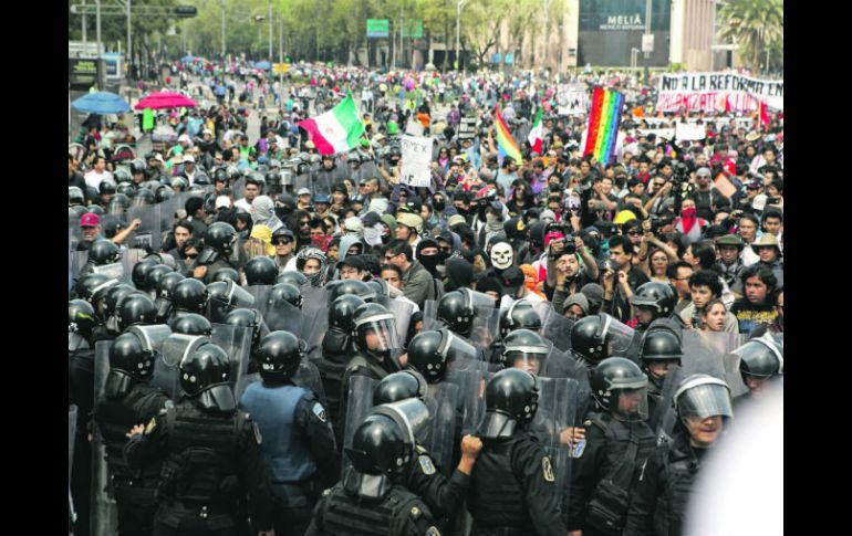 Manifestantes encapuchados y policías antimotines durante los enfrentamientos ayer, cuando se dirigían a la Cámara de Diputados. EFE /