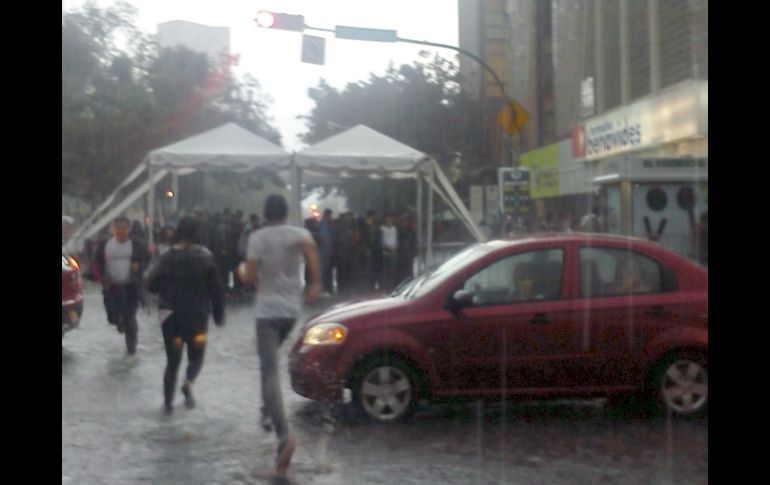 Jóvenes buscando resguardo en toldos o negocios de la zona fueron la escena constante durante la lluvia. EL INFORMADOR /