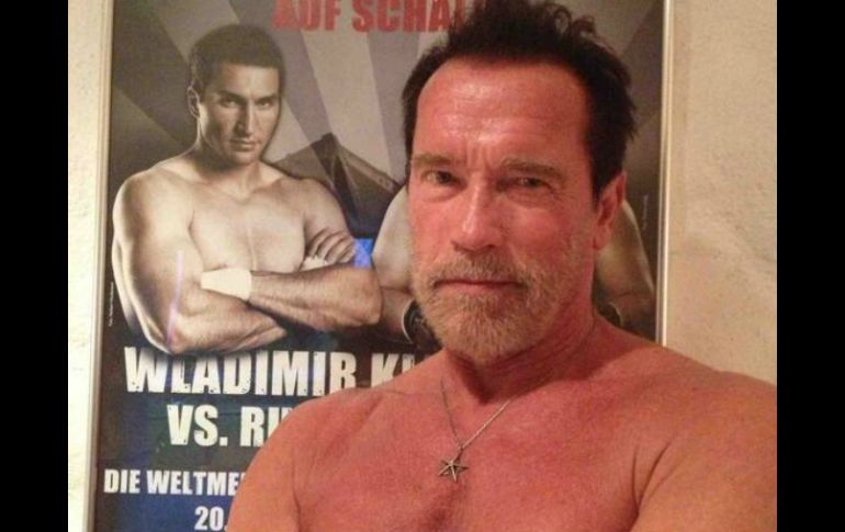 Arnold Schwarzenegger aparece sin camisa y con el póster del boxeador en el fondo. Tomada de @Schwarzenegger en Twitter. ESPECIAL /