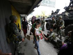 Una familia carga con sus pertenencias mientras caminan por una calle protegida por soldados filipinos durante los enfrentamientos . EFE /