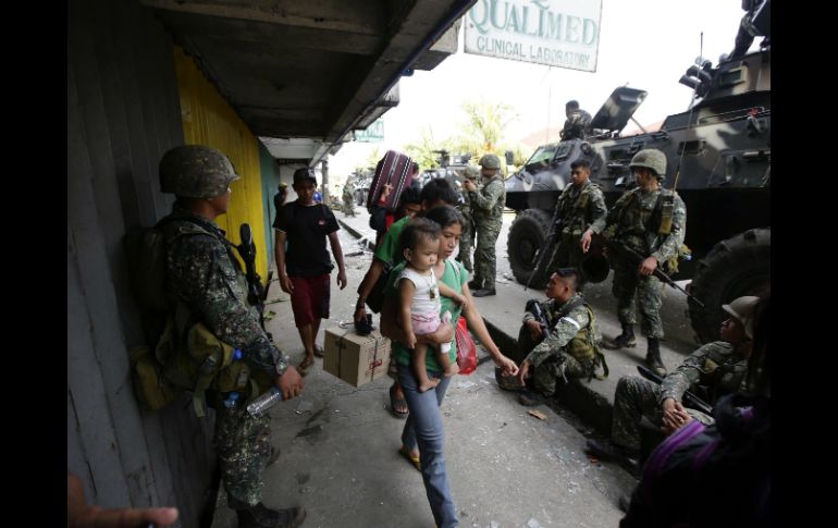 Una familia carga con sus pertenencias mientras caminan por una calle protegida por soldados filipinos durante los enfrentamientos . EFE /