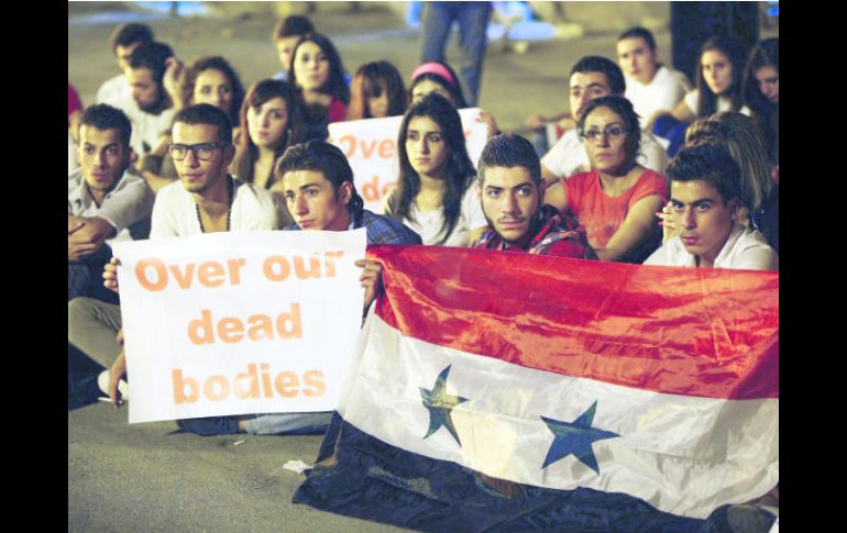 Habitantes de Damasco sostienen pancartas y banderas durante una sentada de protesta contra una eventual acción militar contra Siria. AFP /