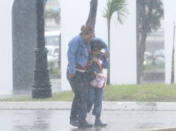 Una mujer y un niño caminan bajo una fuerte tormenta en Veracruz, todos los Estados de México se ven afectados al paso de ''Ingrid''. EFE /