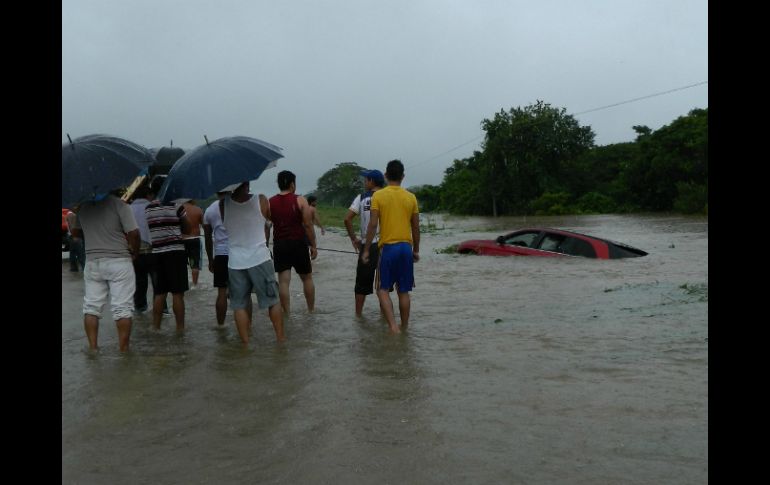 Un grupo de habitantes observa a un vehículo afectado por el desbordamiento del río Guamol, en Oaxaca. EFE /