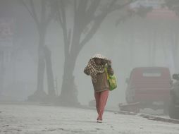 Una aldeana indonesia camina entre la pesada capa de ceniza lanzada por el volcán. AFP /