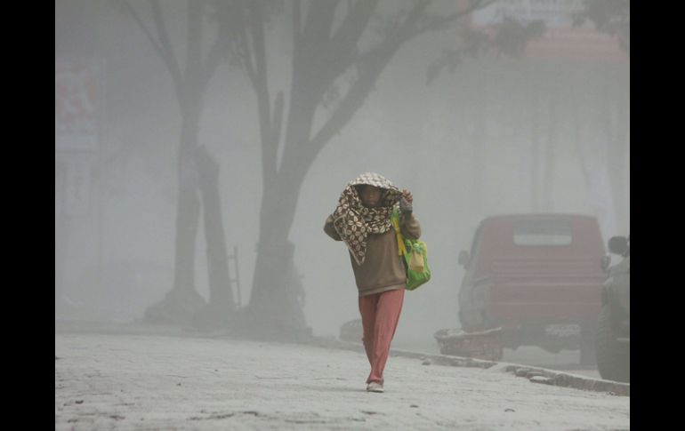 Una aldeana indonesia camina entre la pesada capa de ceniza lanzada por el volcán. AFP /