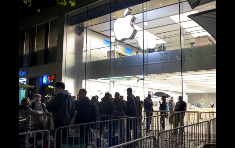 Personas hacen fila afuera de una tienda de Apple antes de ser abierta. EFE /