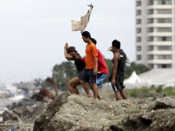 Jóvenes filipinos desafían las fuertes rachas de viento en un pueblo costero en la ciudad de Pasay, al sur de Manila. EFE /