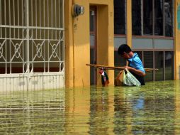 Un joven trata de entrar a su casa en medio de una severa inundación en Tixtla, Guerrero. ARCHIVO /