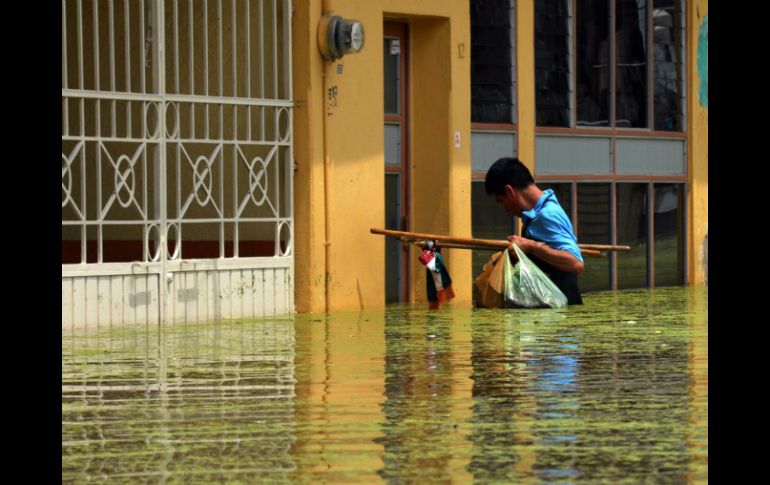 Un joven trata de entrar a su casa en medio de una severa inundación en Tixtla, Guerrero. ARCHIVO /