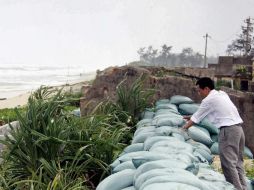 Los habitantes de la costa en el Mar de China Meridional protegen sus casa con bolsas de arena. AFP /