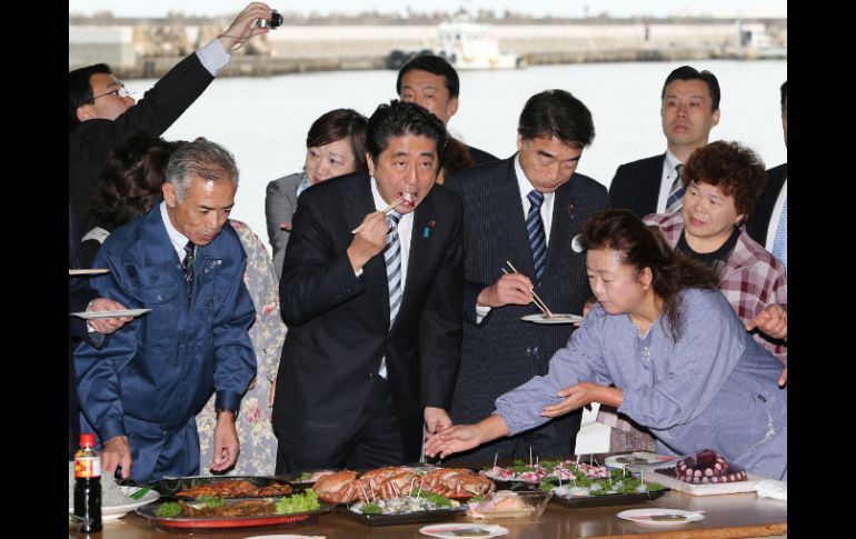 El ministro Abe (c) comió pescado y pulpo capturado cerca del puerto para dejar claro que son productos seguros. AFP /