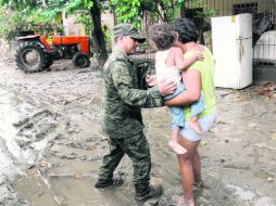 Un militar ayuda a una familia en Coyuca de Benítez. La Sedena desplegó a mil 500 elementos para apoyar con las labores de rescate. AFP /