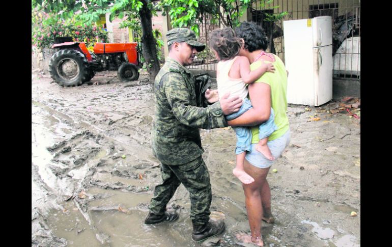 Un militar ayuda a una familia en Coyuca de Benítez. La Sedena desplegó a mil 500 elementos para apoyar con las labores de rescate. AFP /