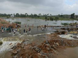 Aldeanos pasan por un camino inundado tras las fuertes lluvias en el distrito Hayat Nagar, en la India. AFP /