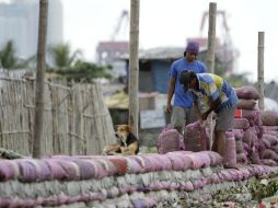 Dos hombres trabajan en la construcción de un dique con sacos de arena ante la previsión del fenómeno. EFE /