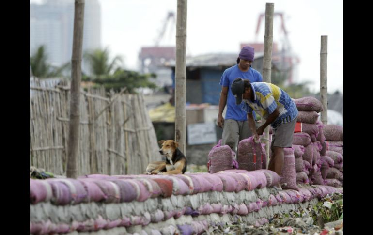 Dos hombres trabajan en la construcción de un dique con sacos de arena ante la previsión del fenómeno. EFE /