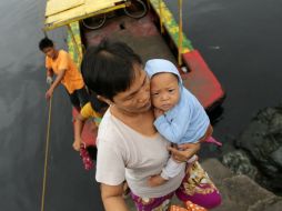 Una mujer atraviesa un río con su bebé en brazos, en una aldea costera en Las Pinas, sur de Manila; durante una evacuación. EFE /